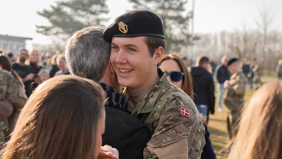 Ein junger Mann in Militäruniform wird umarmt