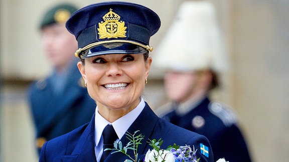 Kronprinzessin Victoria von Sweden während der Militärparade anlässlich ihres Namenstages mit einem Strauß Blumen in der Hand, freudig lächelnd