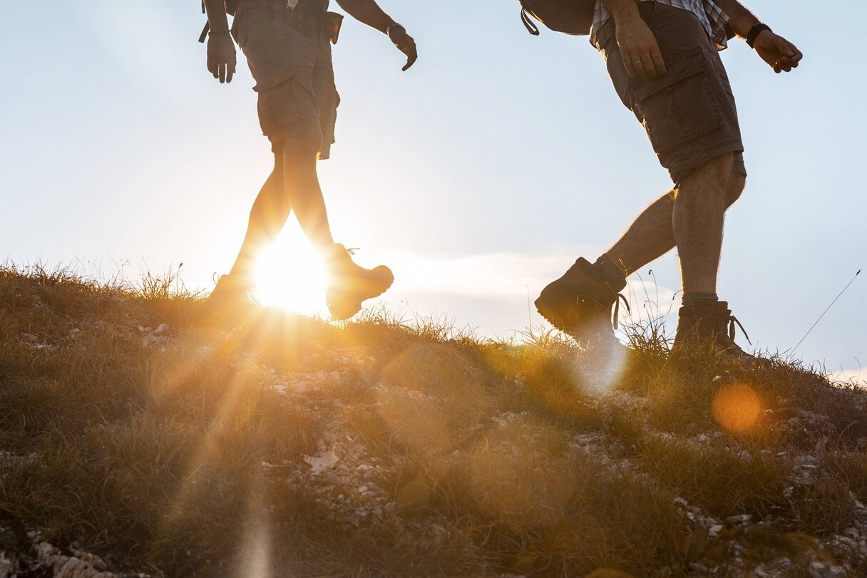 Zwei Männer wandern bei tief stehender Sonne