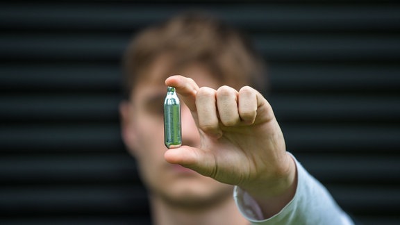 Junger Mann hält eine Lachgas-Kartusche