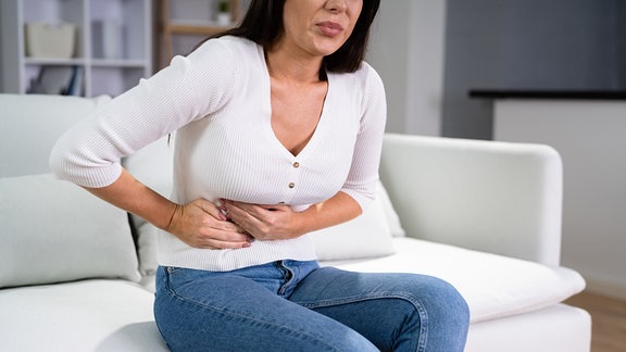 Eine Frau hält sich unter Schmerzen den Bauch