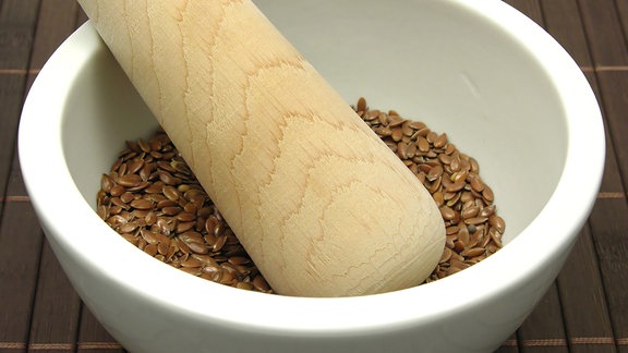 Leinsamen in Porzellanschale mit Mörser