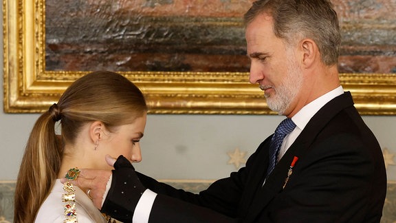 Königg Felipe VI. übergibt seiner Tochter eine Kette.