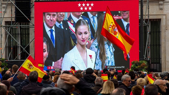 Menschen mit spanischen Flaggen sehen auf einer riesigen Leinwand im Zentrum von Madrid die Live-Übertragung der Vereidigung der Verfassung von Prinzessin Leonor, der ersten Tochter Asturiens und Erbin des Königs, im spanischen Abgeordnetenhaus.