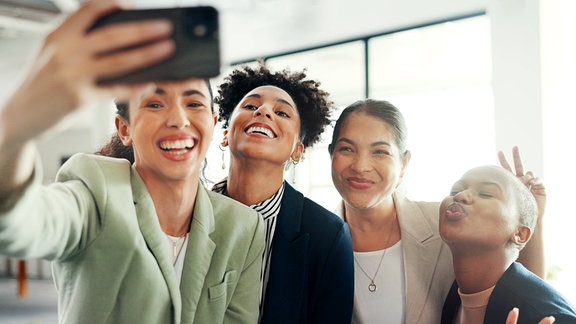 Ein inszeniertes Foto zum Thema Diversität zeigt junge Erwachsene die ein Selfie machen.