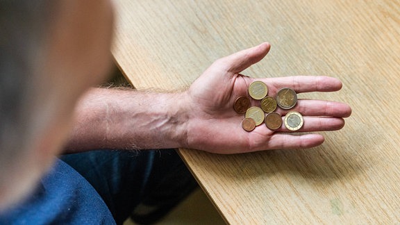 Eine Person hält Euromünzen in einer Hand.