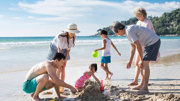 Erwachsene und Kinder an einem Strand
