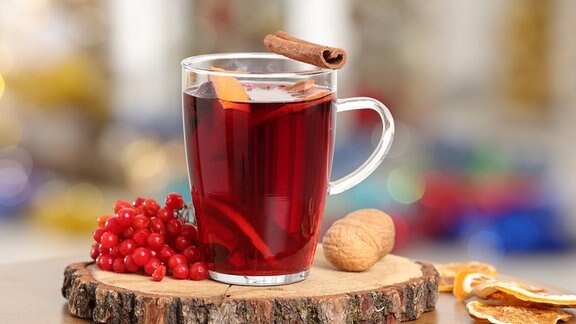 Glühwein in der Tasse mit Zutaten daneben