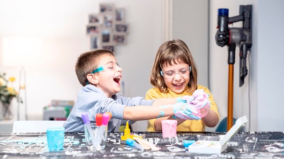 Ein Junge und ein Mädchen spielen am Tisch mit Spielschleim.
