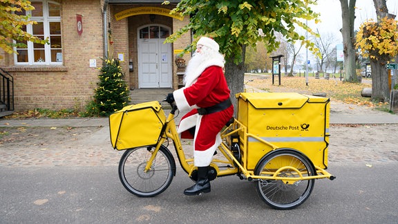 Ein Weihnachtsmann fährt 2021 mit einem Elektro-Fahrrad am Weihnachtspostamt vorbei.