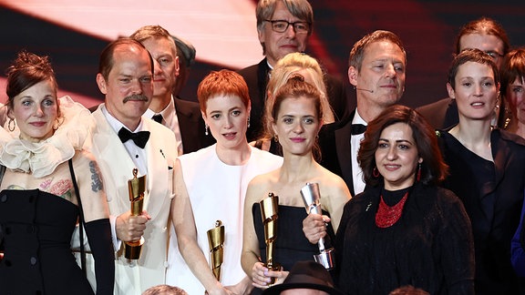 Preisträgerinnen und Preisträger stehen für ein Gruppenfoto auf der Bühne