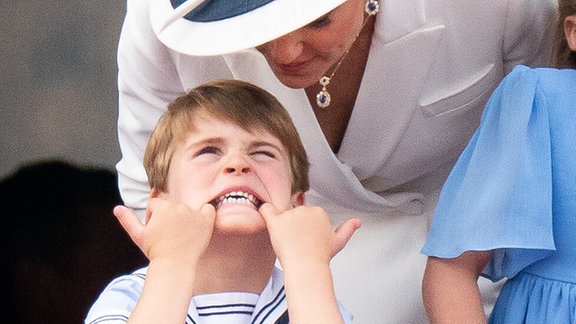Kate (r), Herzogin von Cambridge, spricht mit Prinz Louis, als er auf dem Balkon des Buckingham Palastes das Gesicht verzieht, bei einer Flugzeug-Formation am ersten Tag der Feierlichkeiten zum Platinjubiläum der Queen am 02.06.2022.