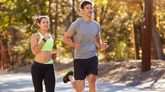Mann und Frau joggen gemeinsam im Park.
