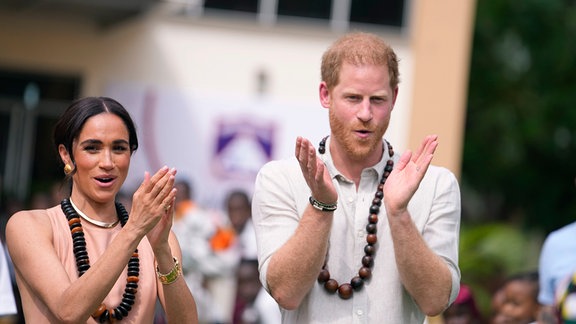 Prinz Harry und seine Ehefrau Meghan gestikulieren, während sie Kinder in der Lights Academy besuchen.