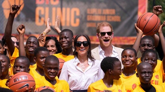 Prinz Harry (Mitte r) und Meghan (Mitte l) posieren für ein Foto mit Kindern während der Giant of Africa Foundation in der Dream Big Basketball Klinik. Prinz Harry und seine Frau Meghan sind in Nigeria, um für die Invictus Games zu werben, die Prinz Harry gegründet hat, um die Rehabilitation von verwundeten und kranken Soldaten und Veteranen zu unterstützen.