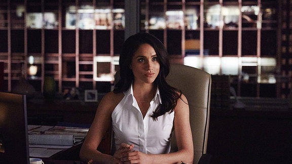 Meghan Markle in einem Still aus der Serie "Suits" an einem Schreibtisch.