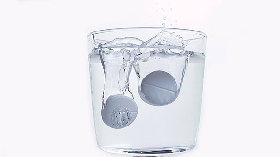 Tabletten in einem Glas Wasser.