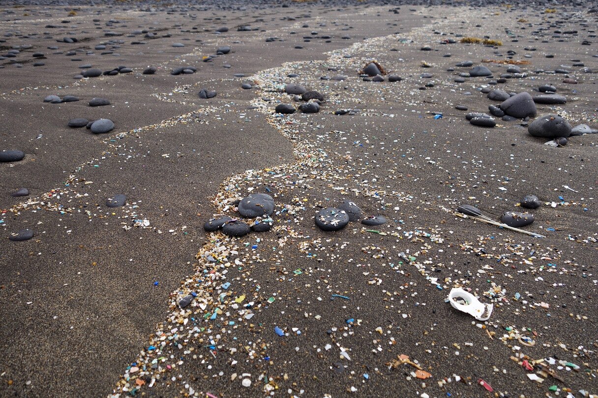 Angespühltes Mikroplastik auf dunklem Lavasand | Bildrechte: IMAGO / Westend61 Angespühltes Mikroplastik auf dunklem Lavasand
