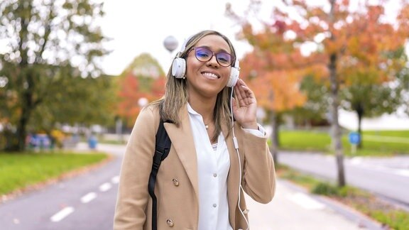 Selbstbewusste Geschäftsfrau, die Musik hört und durch die Stadt läuft.