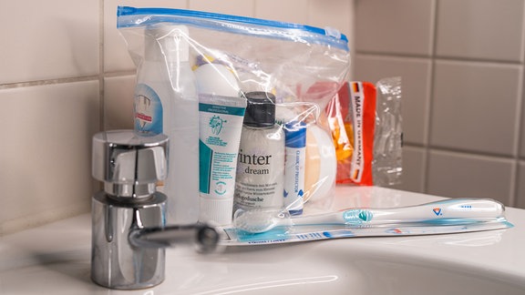 Hygienebeutel steht auf einem Waschbecken, davor liegt eine Zahnbürste
