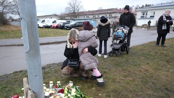Eine Frau weint an einer behelfsmäßigen Gedenkstätte in der Nähe des Campus Risbergska am Rande von Örebro