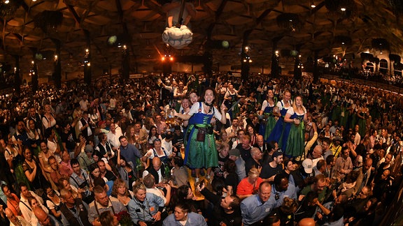Bedienungen feiern mit den Gästen beim traditionellen Kehraus im Hofbräuzelt den Abschluss der Wiesn.