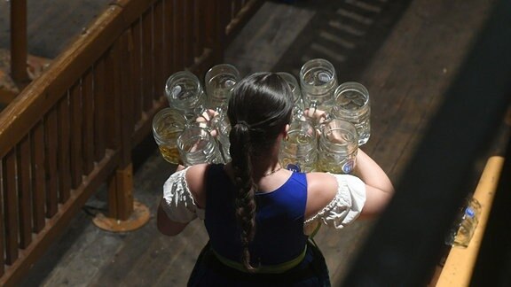 Eine Bedienungen trägt nach dem traditionellen Kehraus im Hofbräuzelt leere Maßkrüge.