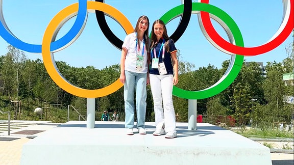 Zwei Personen vor den Olympischen Ringen