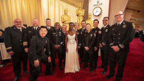 Feuerwehrmänner posieren auf dem roten Teppich bei der Oscarverleihung 2025.