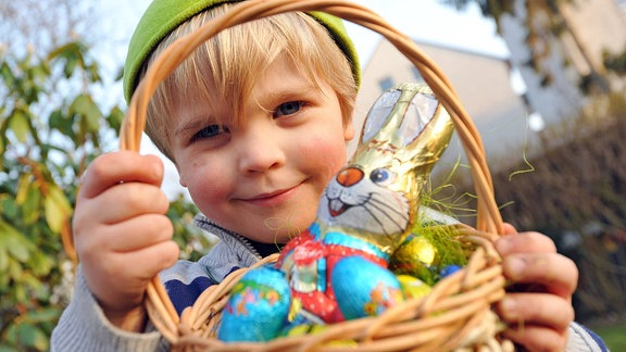 Ein Junge hält ein Körbchen mit Ostersüßigkeiten