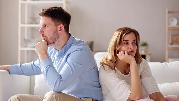 Ein Mann und eine Frau sitzen nebeneinander und schauen in die jeweils andere Richtung