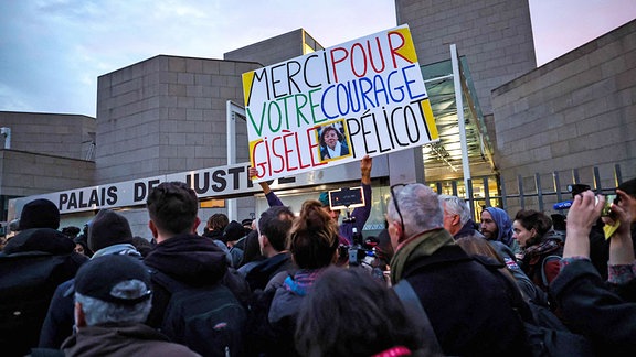 Der französische Künstler und Aktivist Voltuan hält ein Plakat mit der Aufschrift «Danke für deinen Mut, Gisele Pelicot», während Journalisten vor dem Gerichtsgebäude in Avignon Schlange stehen, wo das Urteil erwartet wird.