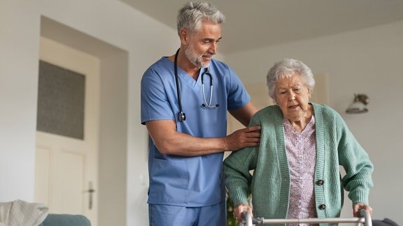 Pfleger stützt Seniorin mit Rollator