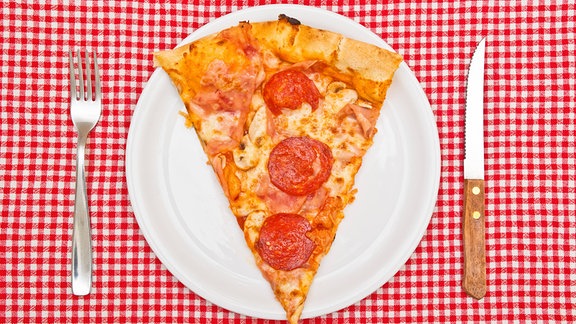 Ein Stück Pizza auf einem Teller auf einer rot-weiß karierten Tischdecke