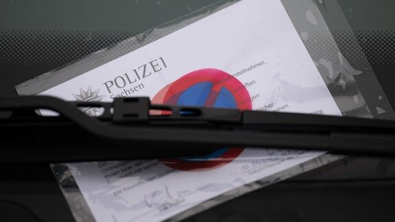 Ein Strafzettel der Polizei Dresden klemmt an einem Fahrzeug unter dem Scheibenwischer.
