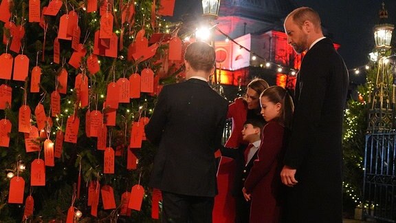 Prinz William und Prinzessin Kate von Wales mit ihren Kindern Prinz George, Prinzessin Charlotte und Prinz Louis betrachten die Botschaften auf dem Freundlichkeitsbaum vor dem Weihnachtsgottesdienst «Together At Christmas» in der Westminster Abbey.