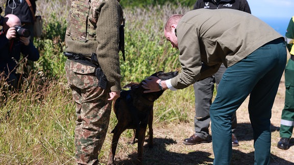 Der britische Prinz William streichelt einen Hund.