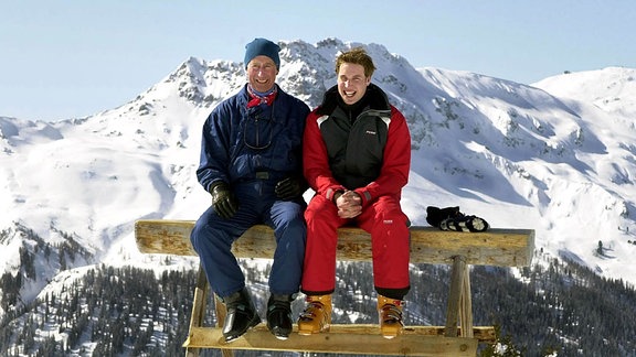 Der Prinz von Wales (links) und sein ältester Sohn Prinz William sitzen 2004, auf den Madrisa-Skipisten oberhalb des Schweizer Dorfes Klosters auf einer Bank.
