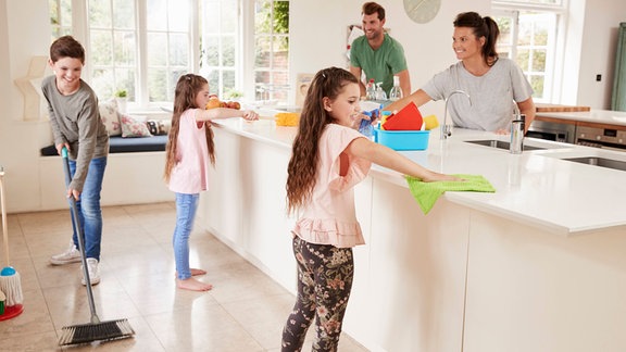 Symbolbild: Eine Familie mit Kindern putzt gemeinsam die Küche