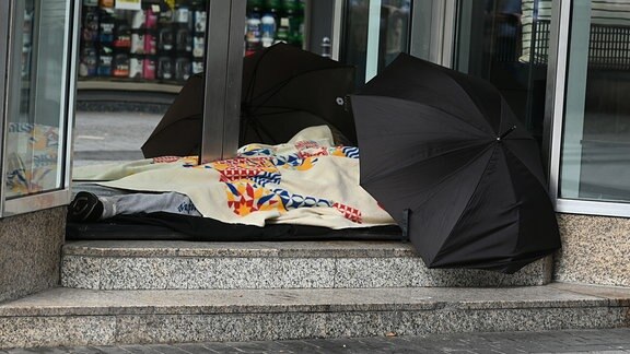 Ein Obdachloser schläft im Eingang zu einem Geschäft in der Innenstadt.
