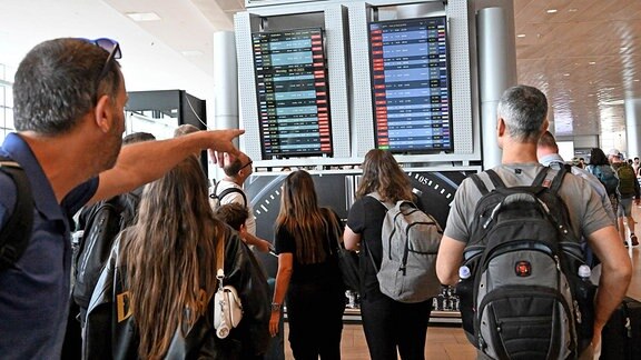 Menschen sehen sich auf dem Flughafen Ben Gurion bei Tel Aviv eine Abflugtafel für gestrichene Flüge an