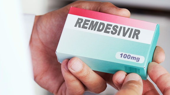 Eine Hande hält eine Packung Remdesivir