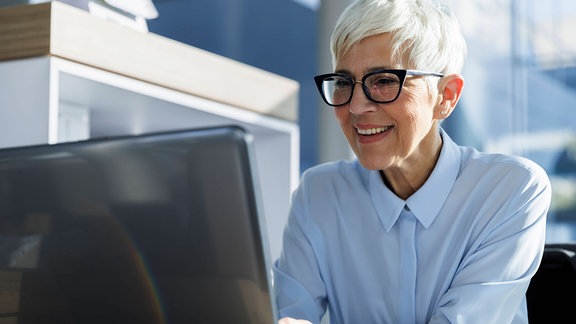 Eine Frau lächelt an einem Laptop