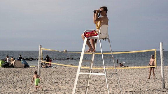 Rettungsschwimmer Lucas Hohmann von der DLRG (Deutsche Lebens-Rettungs-Gesellschaft e.V.) überwacht im Ostseebad Wustrow den Badestrand.