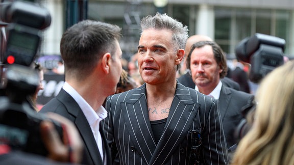 Robbie Williams in einer Menschenmenge vor Fotografen