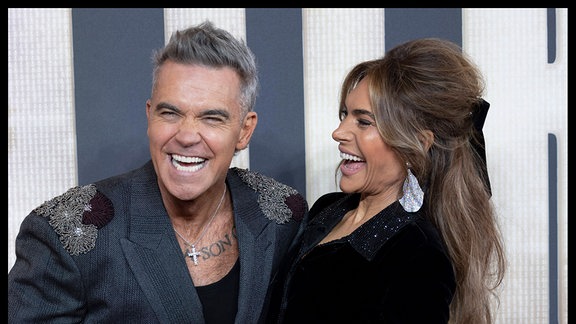Sänger Robbie Williams und Ehefrau Ayda Field lachen.