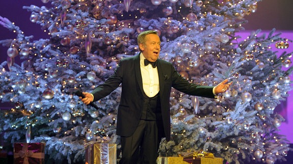 Sänger Roland Kaiser auf der Bühne vor einem großen Weihnachtsbaum
