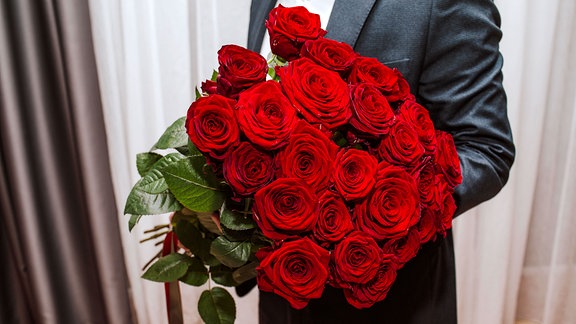 Ein junger Mann mit einem Strauß roter Rosen