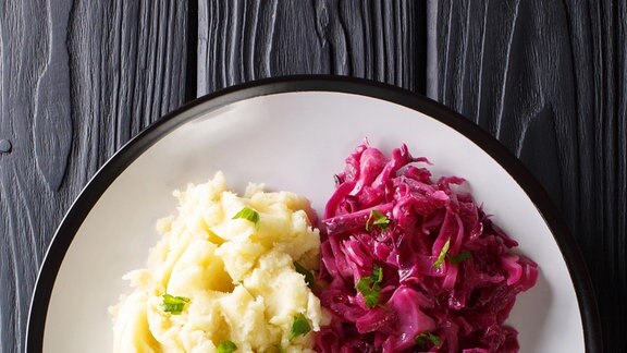 Rinderrouladen mit Bratensoße auf einem Teller, serviert mit Kartoffelpüree und Rotkohl