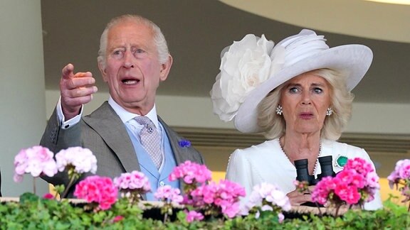 König Charles III. und Königin Camilla reagieren während der King George V. Stakes am dritten Tag von Royal Ascot auf Ascot-Rennbahn.